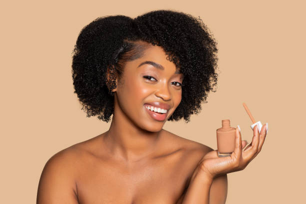 istock Smiling woman holding foundation bottle on beige background 2153103986