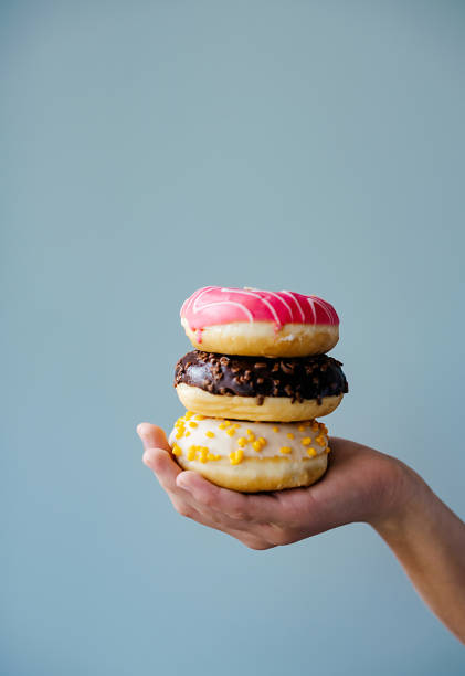 istock Hand holding three donuts, baked goods with staple food ingredients 2153104012