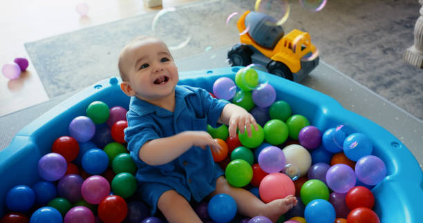 istock Baby, boy and smile in home on pool with plastic balls for fun, growth and child development. Living room, toddler and happy with childhood memories to enjoy in lounge with toys, games and laughing 2153106372