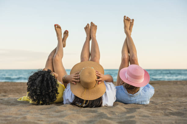 istock Summer fun, friends relaxing on the beach at sunset 2153107378