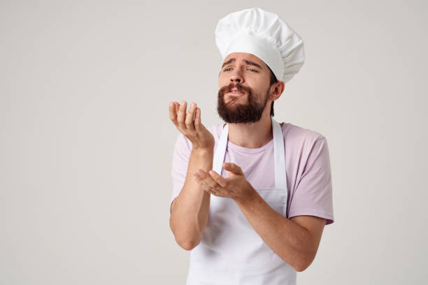 Cheerful male chef in uniform cooking food kitchen light background. High quality photo