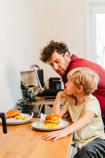 istock Father and son eating hamburger at home 2153111368