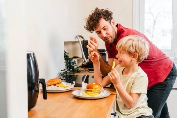 istock Father and son eating hamburger at home 2153111434