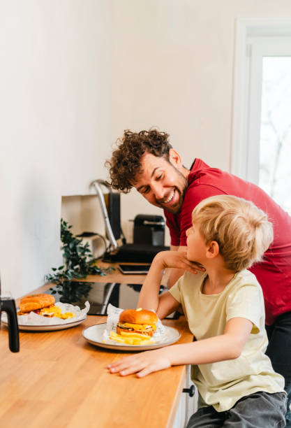 istock Father and son eating hamburger at home 2153111446