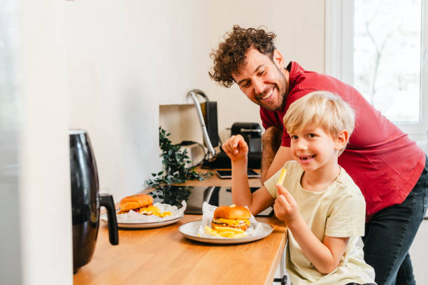 istock Father and son eating hamburger at home 2153111536