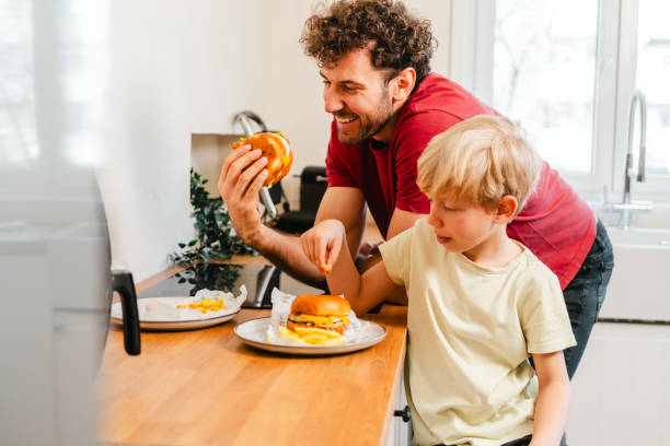 istock Father and son eating hamburger at home 2153111551