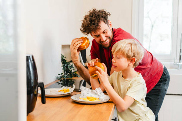 Father and son eating hamburger at home