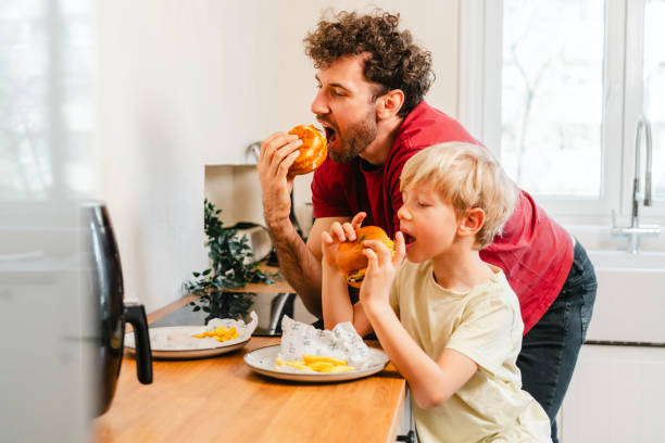 istock Father and son eating hamburger at home 2153111569
