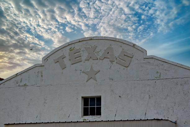 Texas the lone star state spelled out on arch building design in Marfa Texas with dramatic sunset clouds in background.