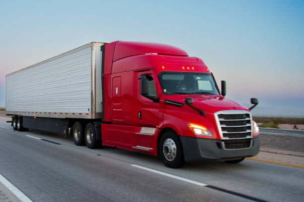 istock Brightly Red Colored Semi-Truck Speeding on a Four-Lane Highway 2153115821