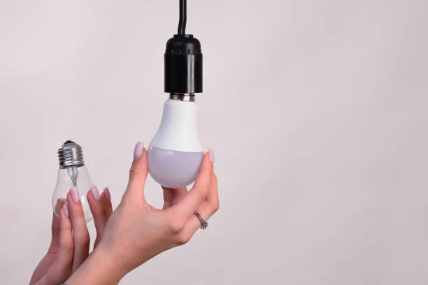 istock LED lamp and incandescent bulbs. In the hand 2153116970