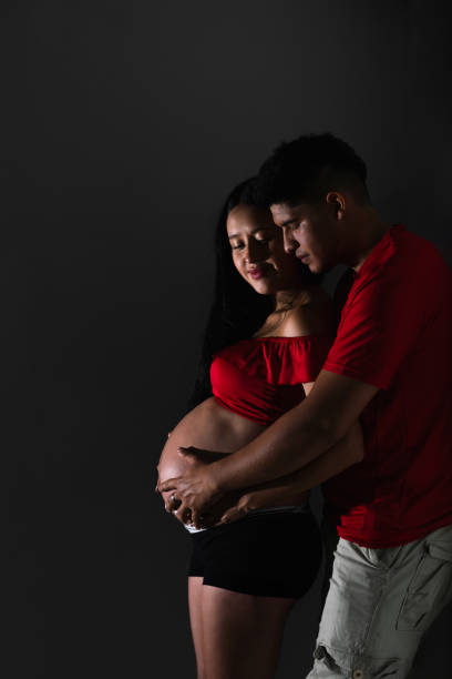 istock young latin couple, man embracing his wife from behind while touching her belly, happily waiting for their baby 2153117937