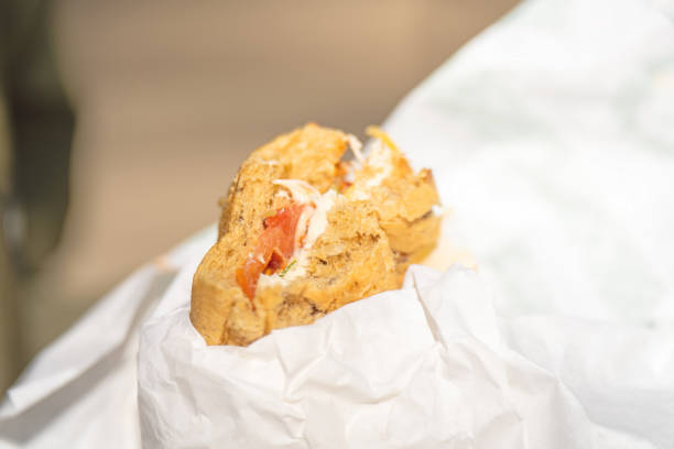 Bitten sandwich with rye bread, tomato, and white sauce