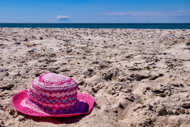 Beach bag with towel, book and sunscreen on sand