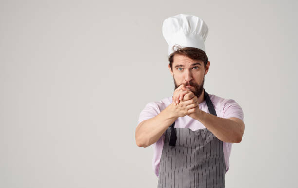 istock A cook in a headdress is gesturing with his hands on a light background, success emotions 2153131343