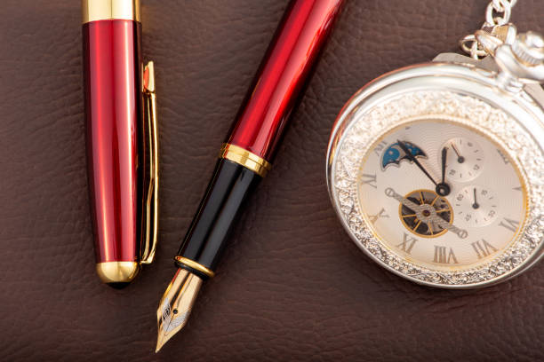 istock Fountain pen and antique pocket watch on leather surface, selective focus 2153132570