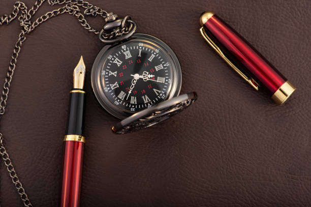 istock Fountain pen and antique pocket watch on leather surface, selective focus 2153132580