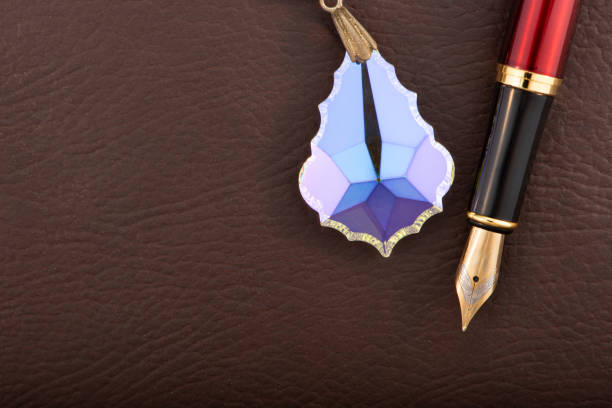 Fountain pen and crystal positioned on brown leather surface, selective focus
