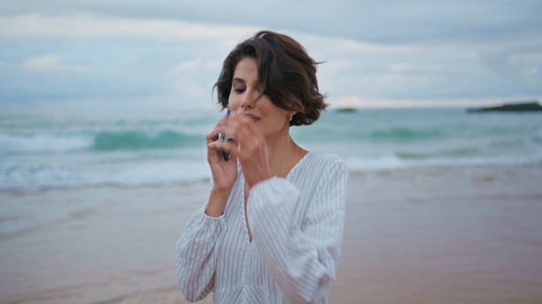 istock Friendly girl talking cellphone at beautiful ocean waves. Calm model going shore 2153135918