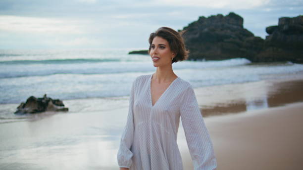 istock Beautiful brunette walking shore on cloudy day. Smiling lady enjoy summer coast 2153140338