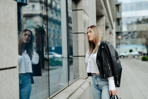 istock Blond Female Fixing Hair By Using Window Reflection Outside 2153141028