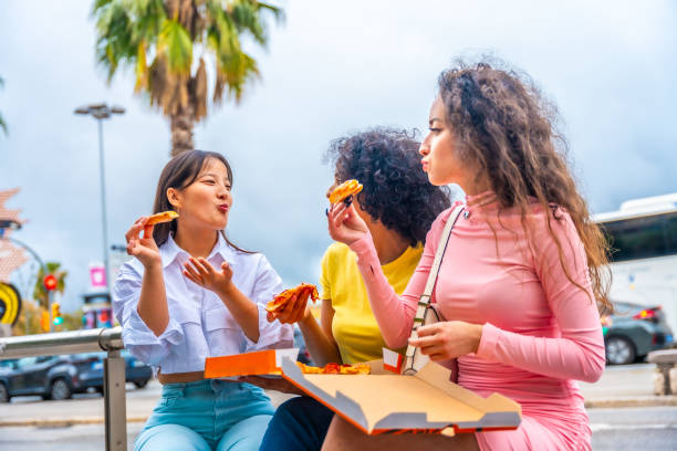 istock Multi-ethnic friends sharing pizza sitting on street 2153152046