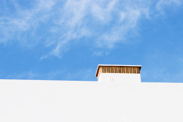 White wall and chimney against blue sky with light clouds. Taken in the Algarve region in South of Portugal.