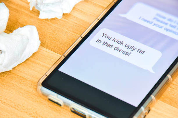 istock Concept of Cyberbullying or internet trolling harassment on smartphone screen unpleasant text message remarks. Selective focus on the text. 2153152563