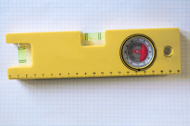 Yellow building level against the background of a checkered notebook sheet close-up.