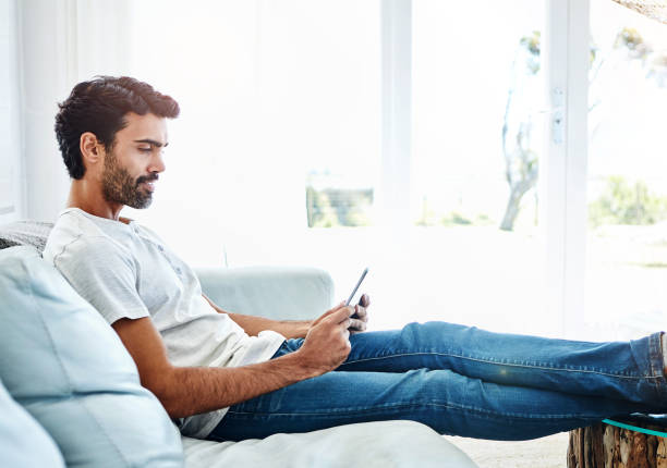 istock Sofa, man and tablet in home or relax, scrolling and online for internet search and reading blog for streaming website. Email, social media and communication technology, comfort and weekend break 2153154313