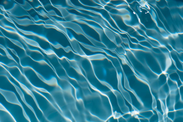 Bluewater waves on the surface ripples blurred. Defocus blurred transparent blue colored clear calm water surface texture with splash and bubbles. Water waves with shining pattern texture background.