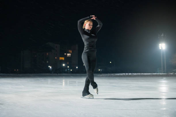 istock Beautiful young woman ice skating and performing short program 2153161401