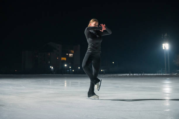 istock Beautiful young woman ice skating and performing short program 2153161427