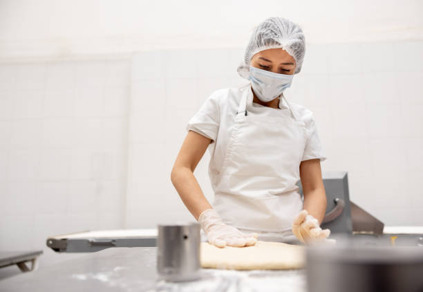istock Baker working at an industrial bakery kneading the dough 2153163546