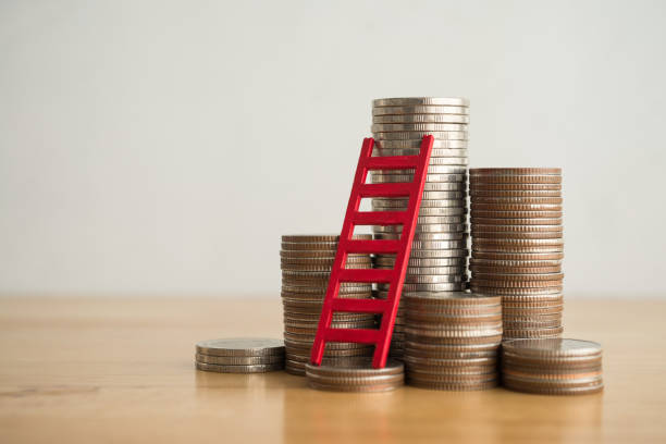 istock Red ladder and stack coin on wooden table with white wall background copy space. 2153168045