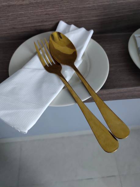 istock Gold or Brass Spoon and Fork Cutlery Resting on Tissue Paper, atop a Small Plate 2153168947