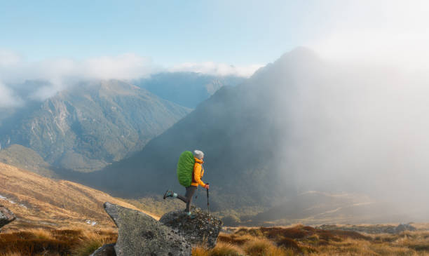 istock Woman with a backpack and a trekking pole is hiking on a rock mountain. 2153169053