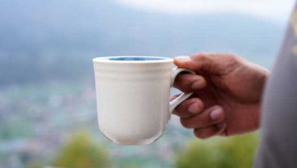 istock Man holding cup of coffee in hand on mountain 2153175973