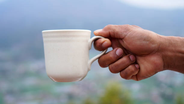 istock Man holding cup of coffee in hand on mountain 2153175974