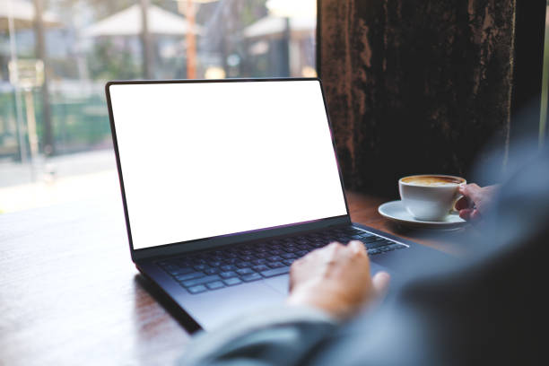 istock Mockup image of a woman working on laptop computer with blank white desktop screen while drinking coffee in cafe 2153177492