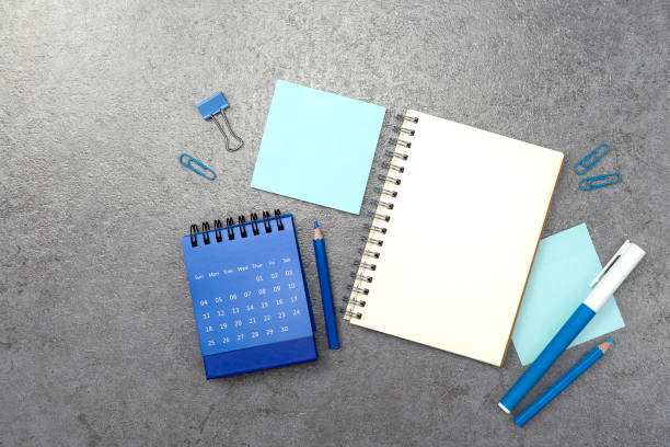 Notebook and blue stationery on stone texture background. Work desk space