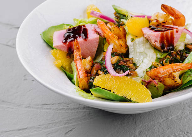 Vibrant bowl of seafood salad with succulent shrimp and citrus segments on a bed of greens