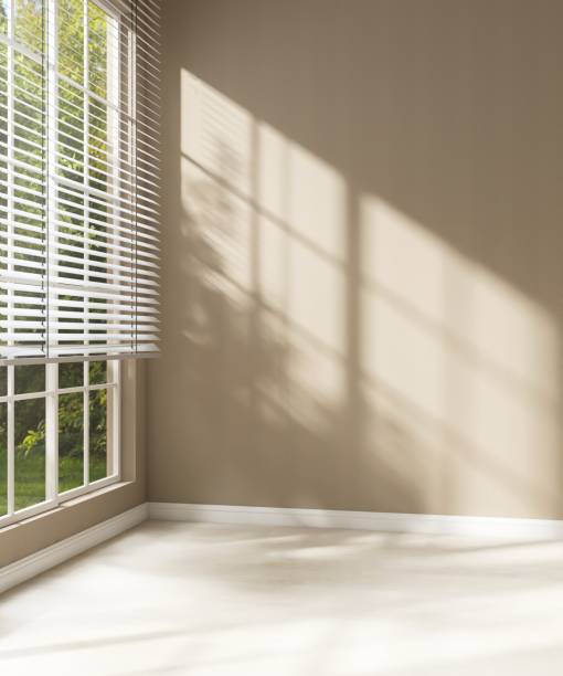 istock Empty room with brown wall in sunlight from window blind to backyard, tree shadow on wood laminated floor 2153184498