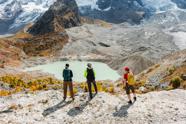 istock Three friends hiking in mountains, standing and looking at mountain lake 2153185190