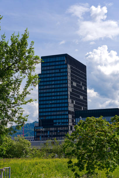Black office tower with green trees in the foreground at Swiss City of Zürich on a sunny spring afternoon. Photo taken May 14th, 2024, Zurich, Switzerland.