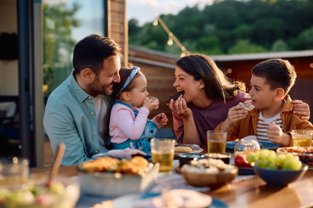 istock Happy family having fun while eating donuts at picnic table on  patio. 2153193724
