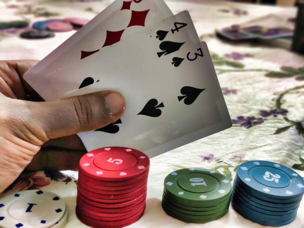 Picture of poker playing chips arranged and a person holding cards on a poker table in a casino