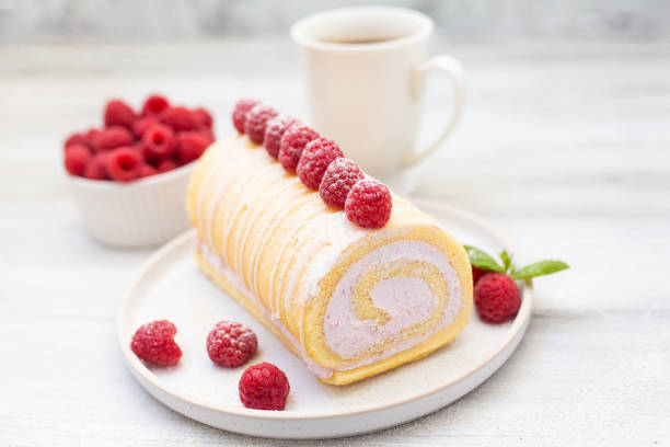 Tasty roll cake, sponge roll, Swiss roll  stuffed with cream cheese ,decorated with fresh raspberries.