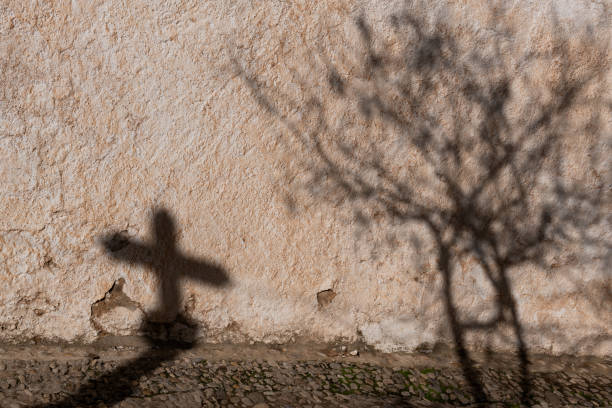istock Shadow of a cross and a tree on a stone building in Spain. 2153196142