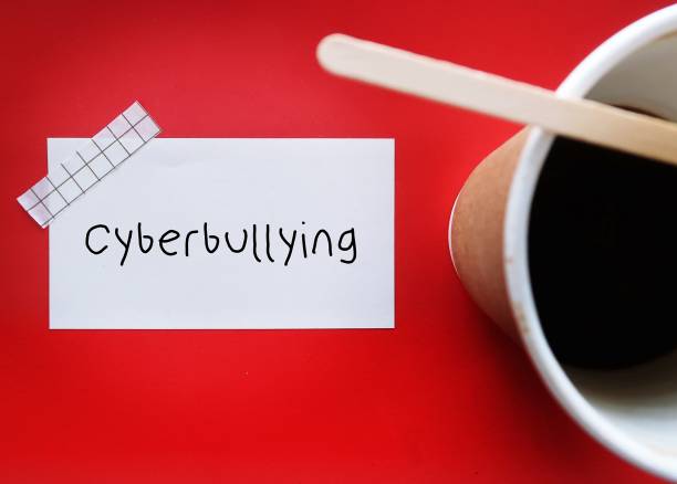 Coffee cup on red background with handwritten text note CYBERBULLYING, bullying that takes place over digital social media, posting or sharing negative, harmful, mean personal content online causing embarrassment or humiliation taza de café sobre fondo rojo con nota de texto escrita a mano ciberacoso, acoso que tiene lugar a través de las redes sociales digitales, publicación o intercambio de contenido personal negativo, dañino y mezquino en línea que causa vergüenza o humi